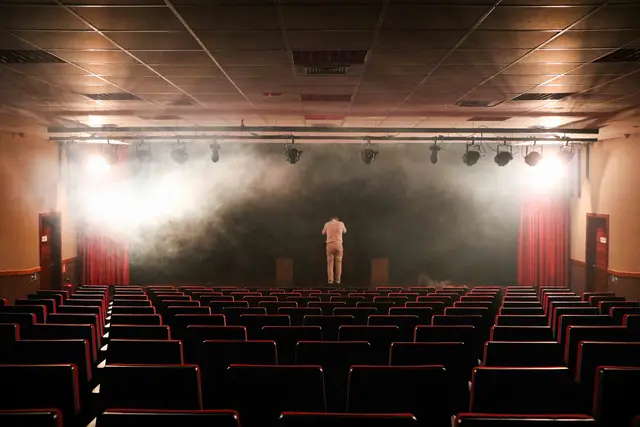 Palco iluminado com fumaça visto da plateia do teatro